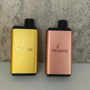 Elegant gold and copper vaping devices showcasing TRUEKE branding against a textured gray background.